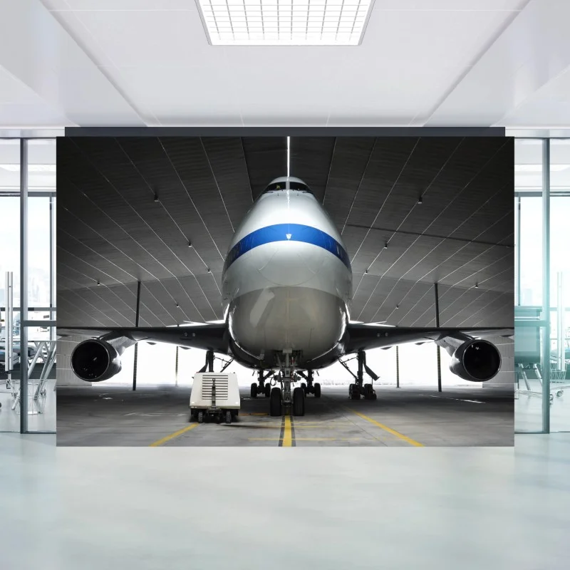 Fotomural vista frontal e imponente de avión en hangar