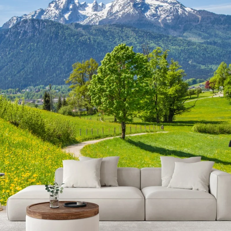 Fotomural paisaje alpino con sendero entre prados floridos y picos nevados