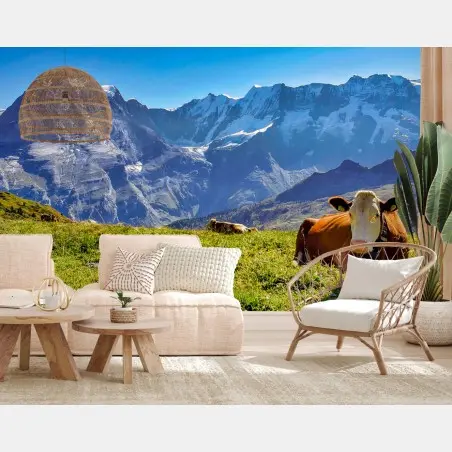 Fotomural vaca descansando en pradera alpina frente a montañas nevadas – Pixers®